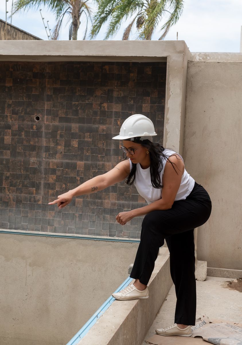Angela Santos, de capacete, apontando um detalhe da parede durante a vistoria de uma obra